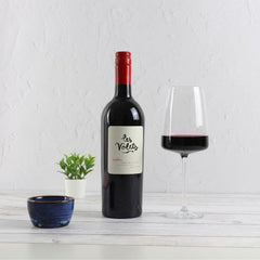 Bottle of Les Volets red wine with a glass on a white surface