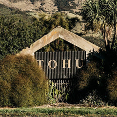Metal sign with 'TOHU' on a natural background